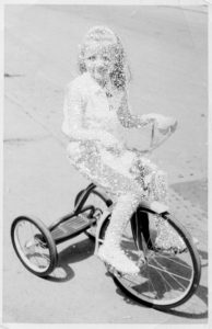 Young_girl_in_white_sitting_on_tricycle