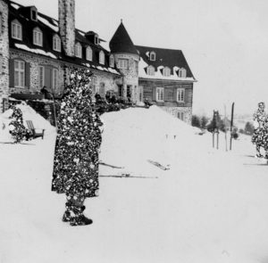 Profile_of_woman_in_black_coat_with_skiers_in_the_background